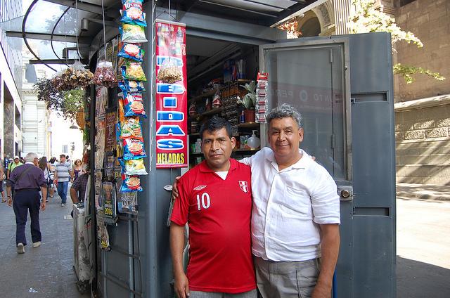 El peruano Juan González, a la izquierda, y el chileno Luis Monsalve se abrazan ante el quiosco del segundo, en la Plaza de Armas de Santiago de Chile, en una fraternidad ajena al diferendo limítrofe binacional que dirimió la Corte de Justicia de La Haya. Crédito: Marianela Jarroud/IPS