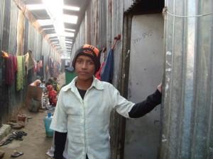 Maruf, de 12 años, vive en este tugurio en Nayanagar, cerca de Daca, la capital de Bangladesh. En el taller mecánico donde trabaja, arregla motores de automóviles de lujo por unos seis dólares al mes. Comparte sus magros ingresos con su familia de cuatro integrantes. Crédito: Naimul Haq/IPS